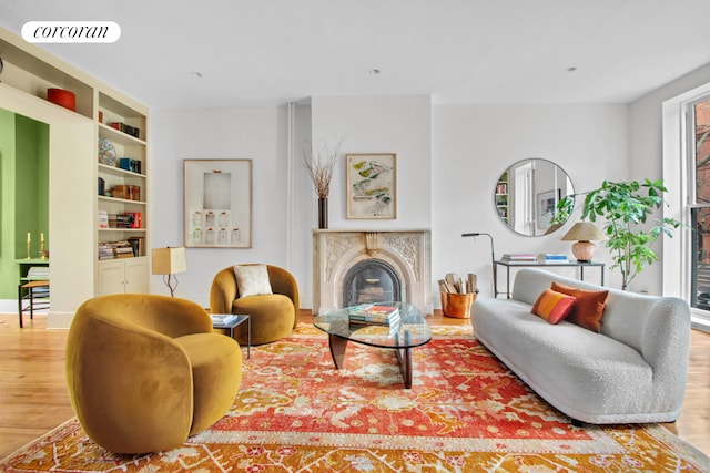 living area with visible vents, a glass covered fireplace, wood finished floors, and built in shelves