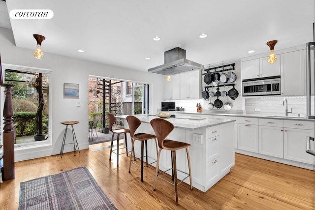 kitchen with backsplash, a center island, range hood, a sink, and stainless steel microwave