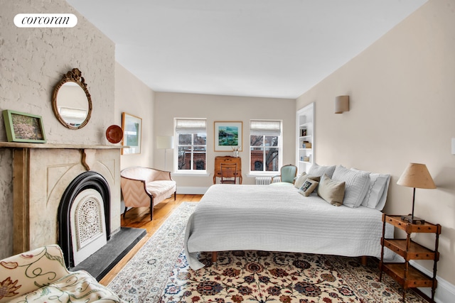 bedroom with baseboards, a fireplace, wood finished floors, and visible vents
