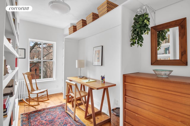 office space with baseboards, visible vents, radiator, and light wood-type flooring