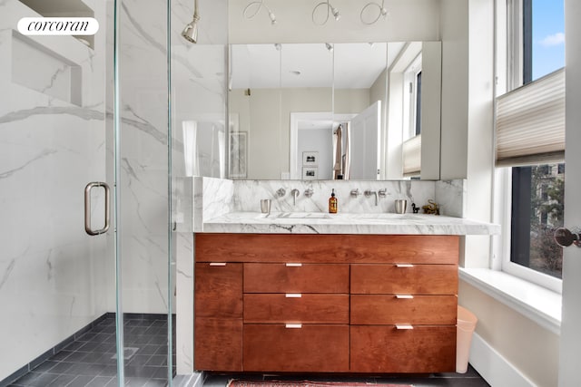full bath with double vanity, a marble finish shower, and decorative backsplash