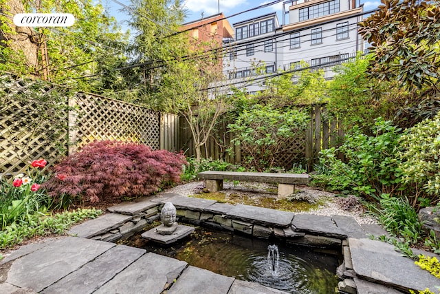 view of yard featuring a garden pond and fence