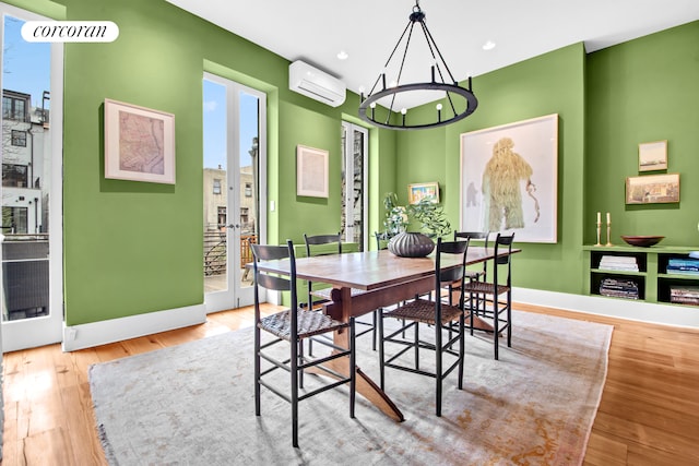 dining room with baseboards, a wall mounted AC, french doors, and wood finished floors