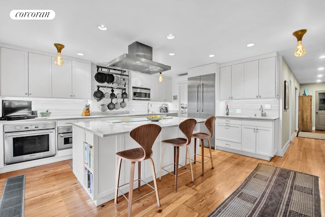 kitchen featuring appliances with stainless steel finishes, range hood, tasteful backsplash, a sink, and white cabinets