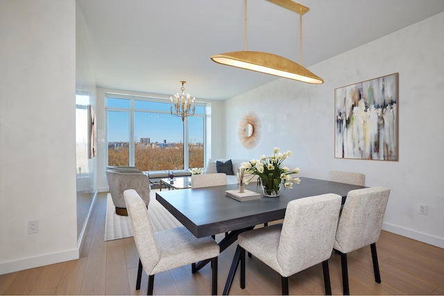 dining room with a chandelier, baseboards, and wood finished floors
