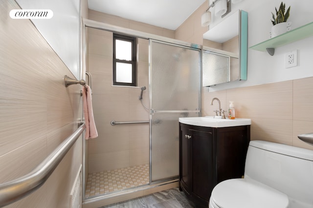 full bathroom featuring vanity, a stall shower, toilet, and tile walls
