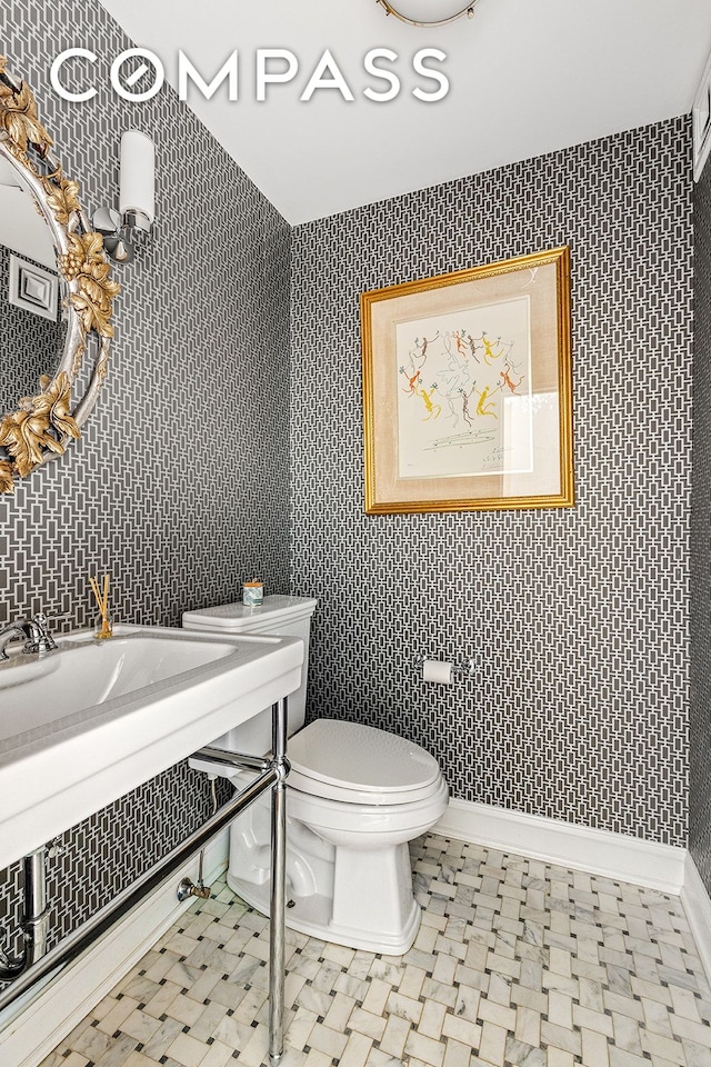 half bathroom featuring toilet and wallpapered walls