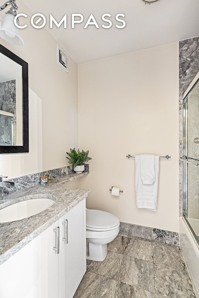 full bath with toilet, vanity, baseboards, and enclosed tub / shower combo