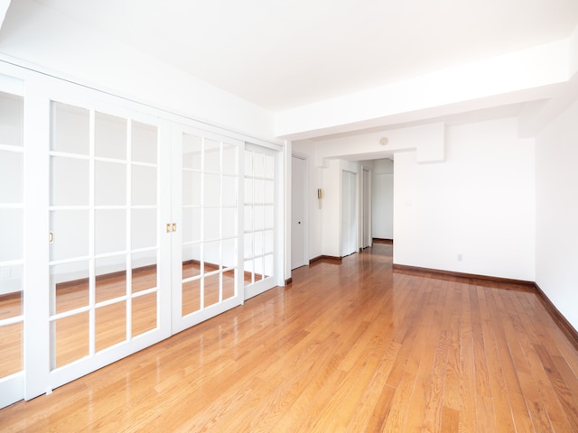 empty room featuring baseboards, french doors, and wood finished floors