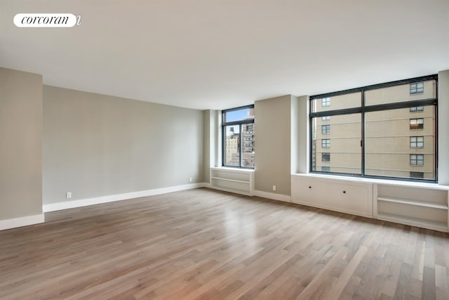 empty room featuring light wood-type flooring and baseboards