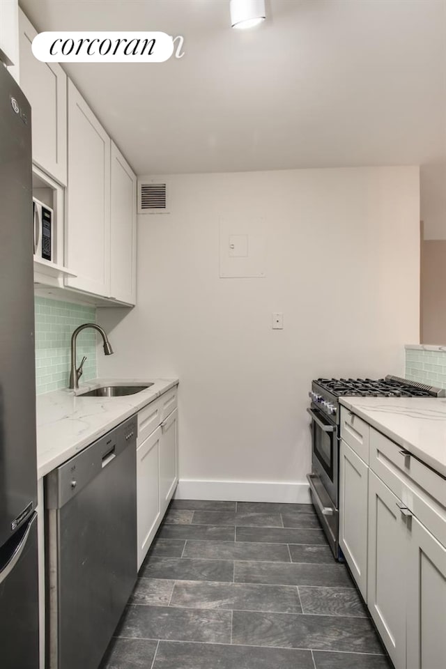 kitchen featuring a sink, appliances with stainless steel finishes, decorative backsplash, and baseboards