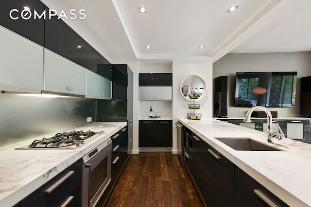 kitchen with a sink, stainless steel gas stovetop, dark cabinets, dark wood-type flooring, and recessed lighting