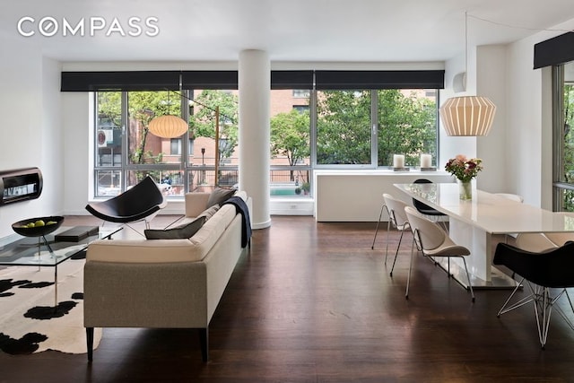 living area with wood finished floors, plenty of natural light, and heating unit