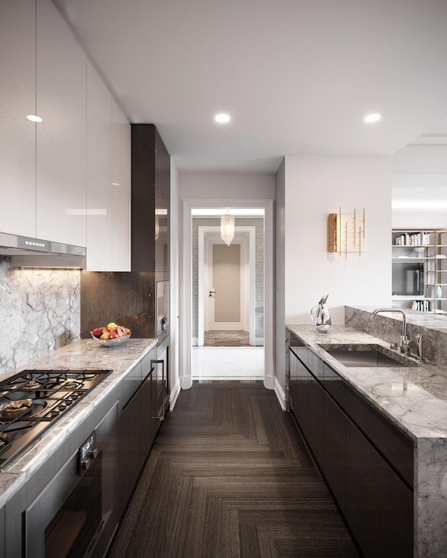 kitchen featuring light stone countertops, stainless steel gas stovetop, modern cabinets, and a sink