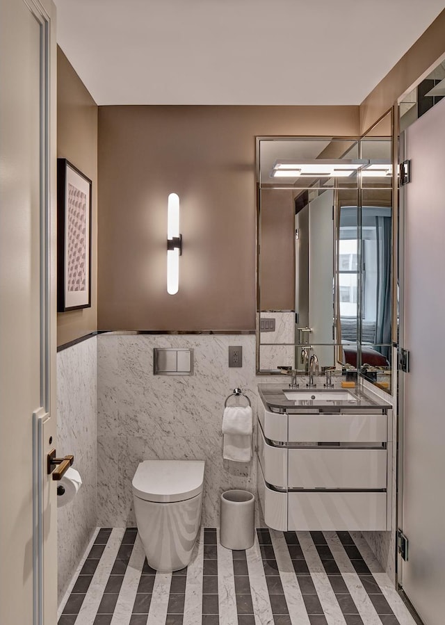 bathroom with vanity, tile patterned flooring, toilet, wainscoting, and tile walls