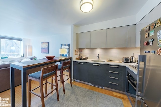 kitchen with stainless steel appliances, a sink, gray cabinets, and modern cabinets