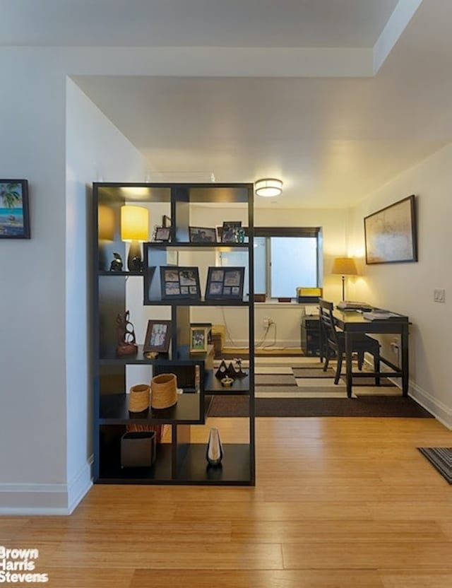 living area featuring a desk, wood finished floors, and baseboards