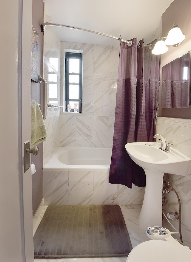 bathroom with tiled shower / bath combo, toilet, and marble finish floor