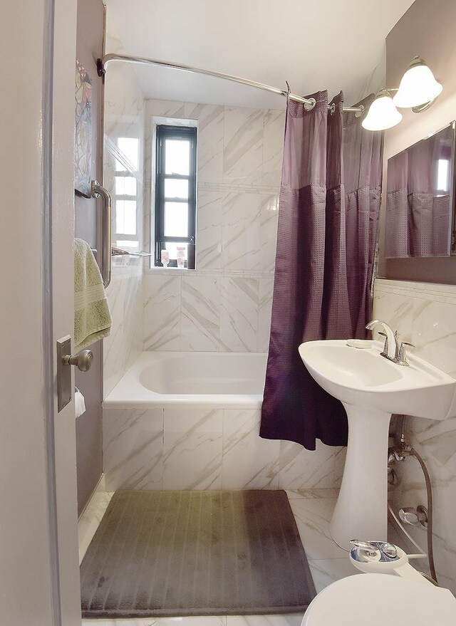 bathroom with tiled shower / bath combo, toilet, and marble finish floor