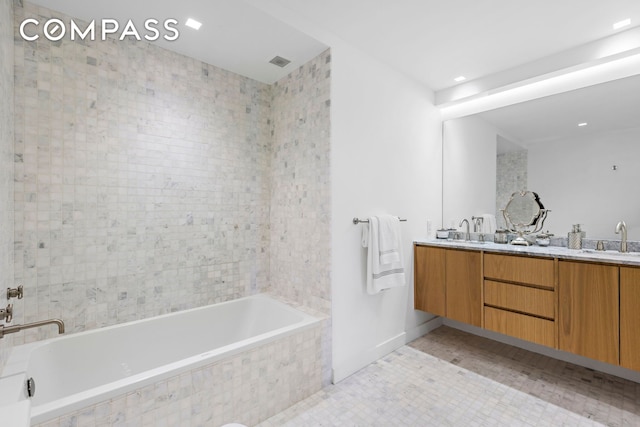 bathroom with double vanity, a relaxing tiled tub, and a sink