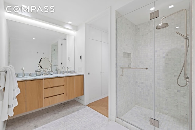 full bath featuring double vanity, a stall shower, and a sink
