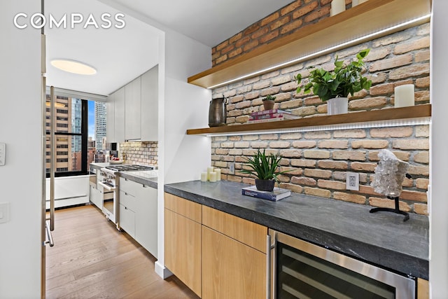 bar with high end range, beverage cooler, light wood-style flooring, a baseboard radiator, and tasteful backsplash