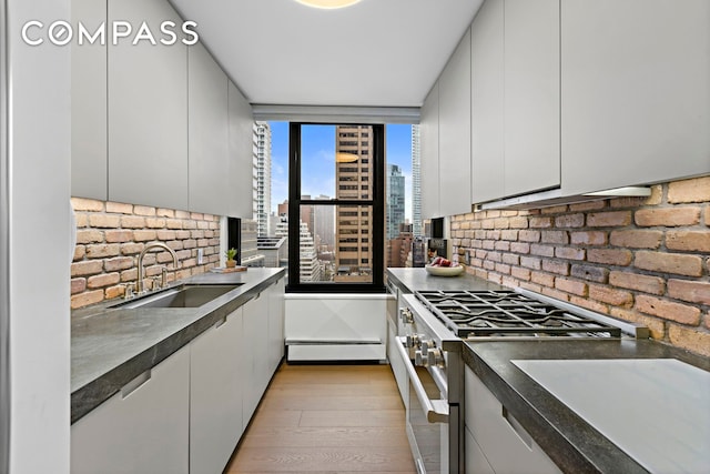 kitchen with a sink, hardwood / wood-style floors, brick wall, a city view, and double oven range