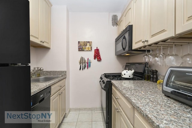 333 E 66th St Unit 7A, New York City, NY 10065 - kitchen with black appliances, a sink, light tile patterned floors, baseboards, and cream cabinetry