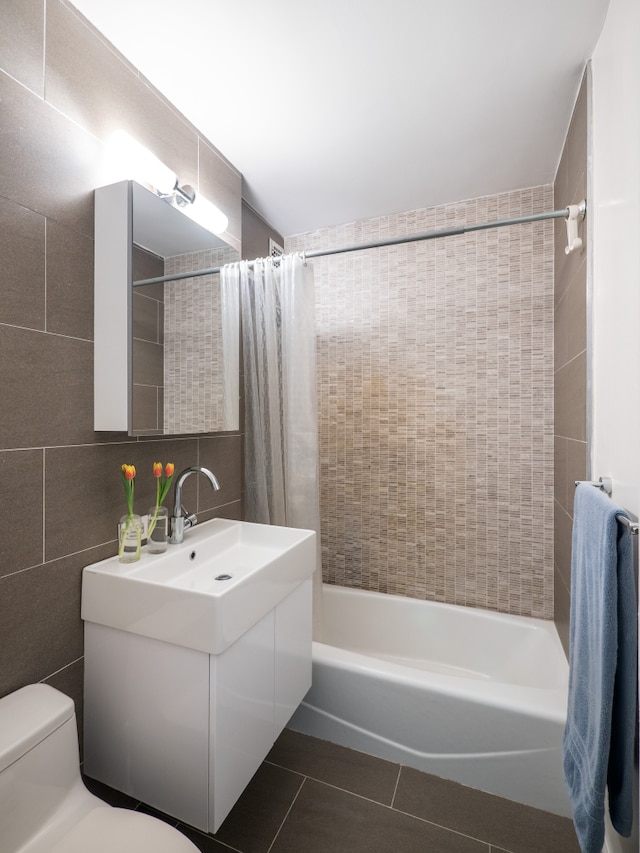 360 W 22nd St Unit 8N, New York City, NY 10011 - bathroom featuring vanity, tile patterned floors, toilet, shower / bath combo with shower curtain, and tile walls