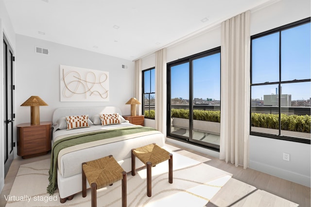 bedroom with light wood finished floors, multiple windows, and access to outside