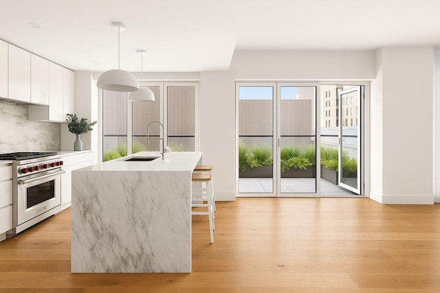 427 E 90th St Unit Ph10, New York City, NY 10128 - kitchen with premium stove, a sink, a kitchen breakfast bar, white cabinetry, and modern cabinets