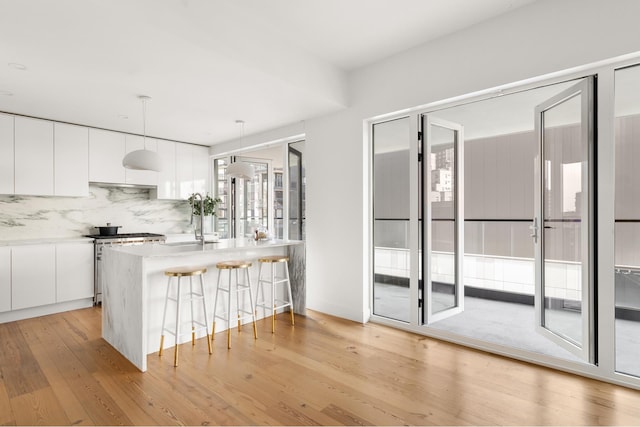 427 E 90th St Unit Ph10, New York City, NY 10128 - kitchen featuring modern cabinets, light wood finished floors, a breakfast bar, white cabinets, and decorative backsplash