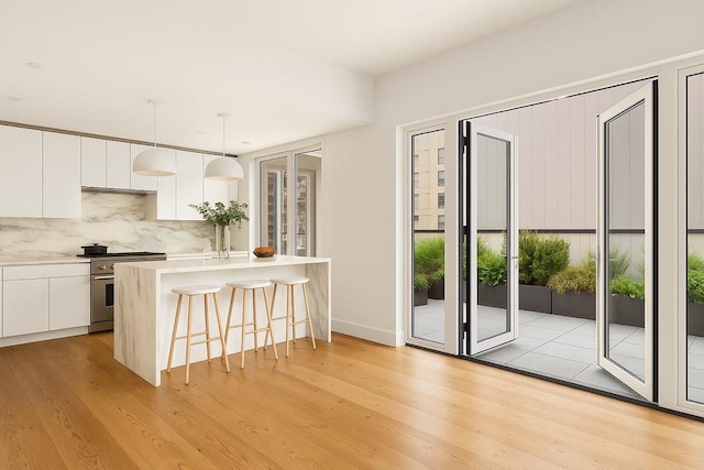 427 E 90th St Unit Ph10, New York City, NY 10128 - kitchen featuring high end stove, white cabinetry, a breakfast bar, and backsplash