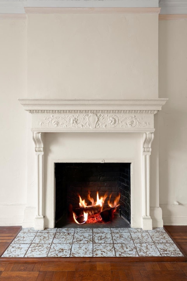 details with a fireplace with flush hearth, baseboards, ornamental molding, and wood finished floors