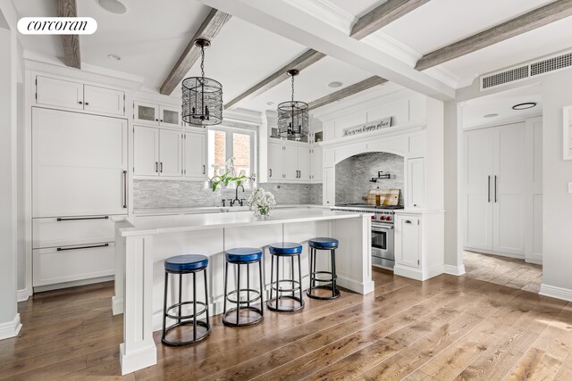 8119 Ridge Blvd, New York City, NY 11209 - kitchen with a notable chandelier, visible vents, high end range, hardwood / wood-style flooring, and white cabinetry