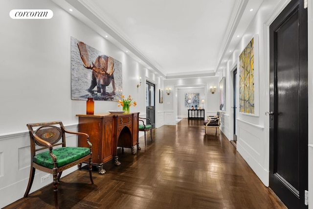 corridor with a decorative wall, ornamental molding, and a wainscoted wall