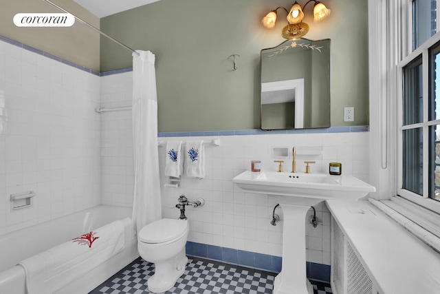 bathroom featuring wainscoting, tile walls, toilet, and shower / bathtub combination with curtain