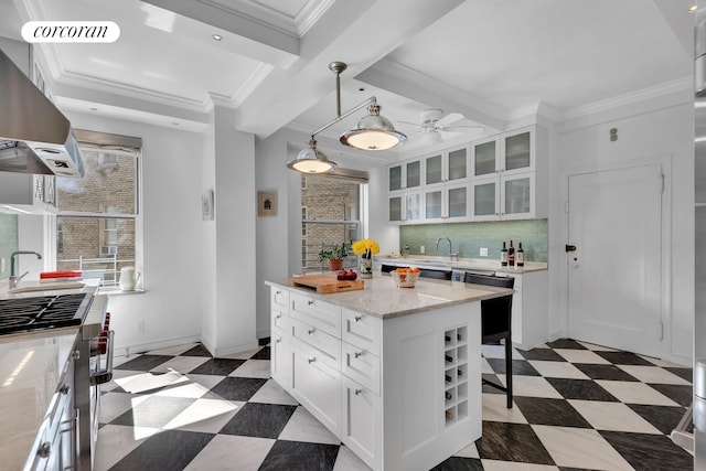 kitchen featuring stainless steel stove, range hood, white cabinetry, a sink, and backsplash