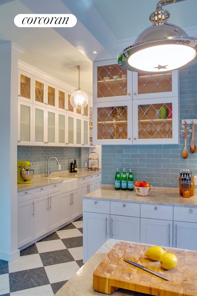 kitchen featuring white cabinetry, hanging light fixtures, tasteful backsplash, and light floors