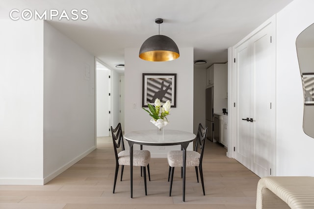 dining room featuring light wood-type flooring and baseboards