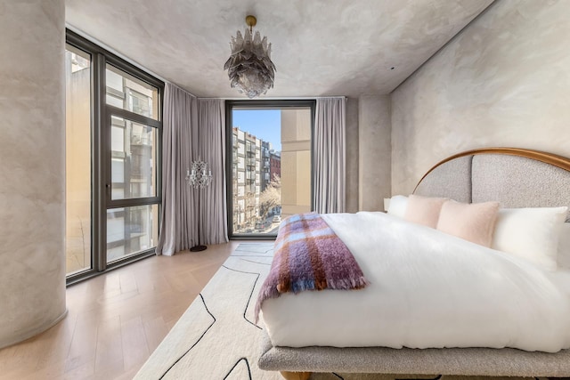 bedroom featuring a wall of windows, access to outside, and wood finished floors