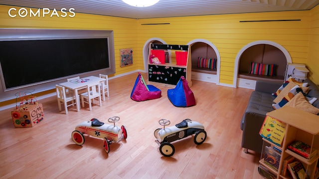 recreation room featuring wood finished floors and wooden walls