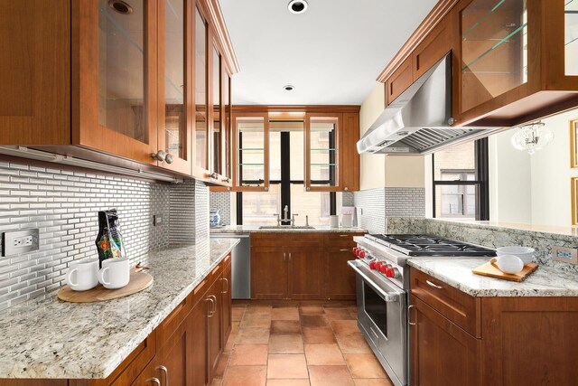 277 W End Ave Unit 9E, New York City, NY 10023 - kitchen featuring appliances with stainless steel finishes, backsplash, brown cabinetry, under cabinet range hood, and a sink