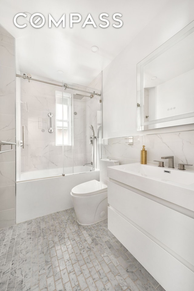 325 E 77th St Unit 1E, New York City, NY 10075 - bathroom featuring tile walls, enclosed tub / shower combo, vanity, and toilet