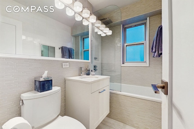 full bath with tile walls, toilet, vanity, and tile patterned floors
