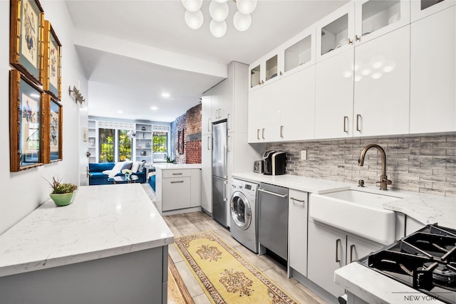 kitchen with glass insert cabinets, decorative backsplash, stainless steel appliances, a sink, and washer / clothes dryer