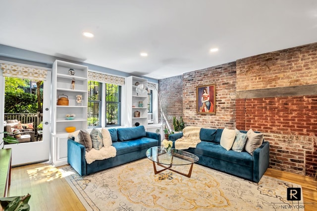 living room featuring brick wall, a wealth of natural light, and wood-type flooring
