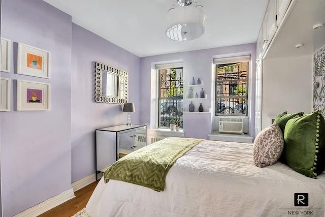 bedroom with wood finished floors, cooling unit, and baseboards