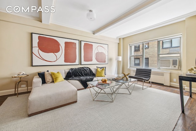 living room featuring wood finished floors, baseboards, beamed ceiling, radiator heating unit, and ornamental molding