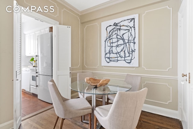 dining room featuring ornamental molding, a decorative wall, and wood finished floors